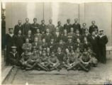 Photograph of a group of young men (servicemen?) in civilian clothes. Also some in naval uniform...